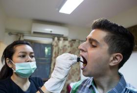 Una donna con mascherina somministra delle gocce a un paziente