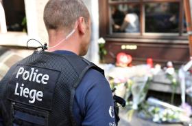 Un poliziotto (con gilet con scritta Police Liege ) guarda i fiori deposti nel luogo dove sono cadute le due colleghe