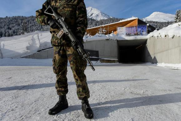 militare svizzero col fucile a tracolla di guardia davanti a un edificio innevato