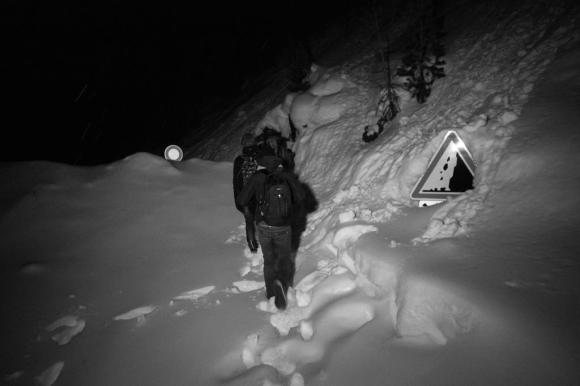 Migranti nella neve cartello di pericolo frane semisepolto.