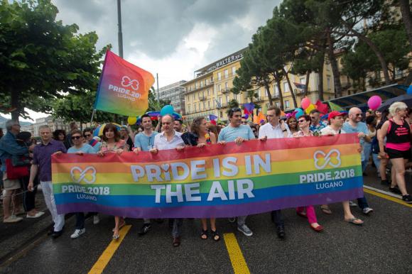 Gruppo di persone in testa a un corteo regge uno striscione con la scritta Pride is in the air