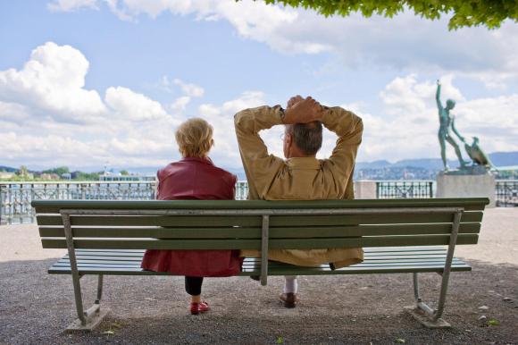 due anziani di spalle seduti su una panchina con di fronte un lago