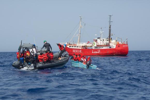Un gommone con parte dell equipaggio di una media imbarcazione soccorre passeggeri di una piccola barca in mare aperto
