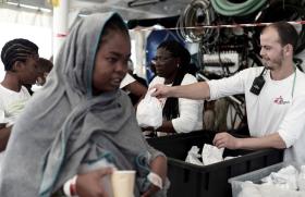 donna davanti a due volontari di medici senza frontiere che distribuiscono dei sacchetti