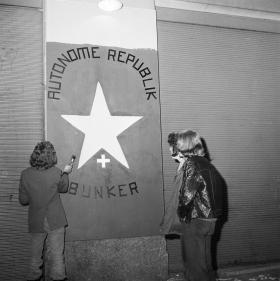due giovani dipingono un cartello con la scritta: Autonome Republik Bunker