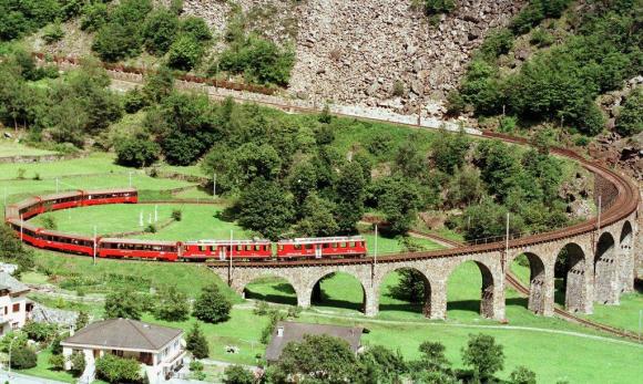 Viadotto ferroviario elicoidale visto dall alto, percorso da un convoglio di 7 carrozze di colore rosso