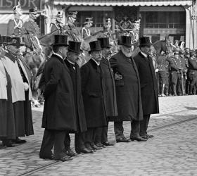 sei uomini con mantello e cilindro sono allineati sulla strada in una foto in bianco e nero