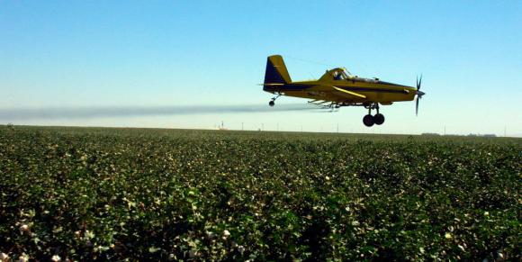 Aereo rilasciante pesticidi in volo sopra un campo