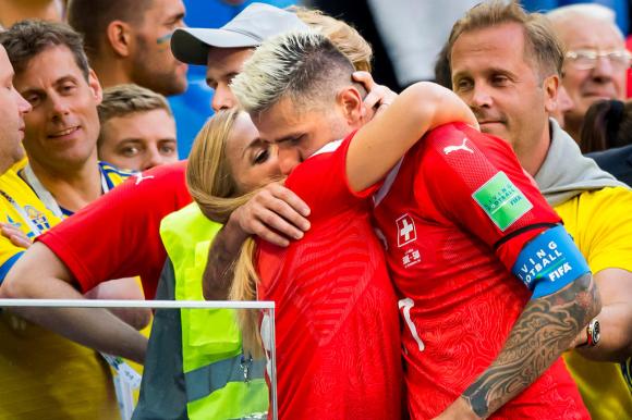 Valon Behrami abbraccia Lara Gut attorniato da tifosi; entrambi indossano la maglietta della nazionale Svizzera