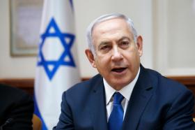 Primo piano del premier israeliano Benyamin Netanyahu, dietro di lui una bandiera israeliana.