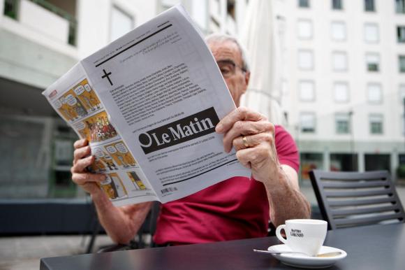Un lettore seduto al bar con l ultima edizione del giornale Le Matin