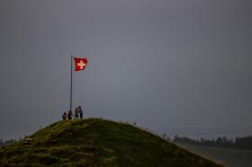 bandiera svizzera e quattro persone sulla cima di una collina