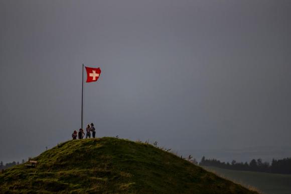 bandiera svizzera e quattro persone sulla cima di una collina