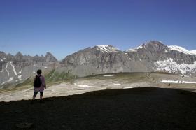 Paesaggio di montagna con poca neve, in primo piano zona d ombra a turista di schiena