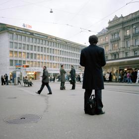 Uomo con paltò di spalle su una piazza a Zurigo