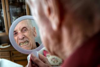 riflesso allo specchio di un anziano che si guarda i denti