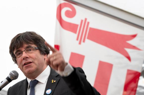 Puigdemont, dito alzato davanti a bandiera giurassiana