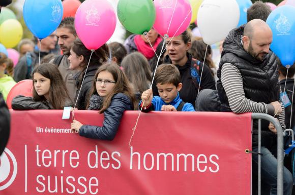 giovani manifestanti con un palloncino davanti a uno striscione di Terre des hommes