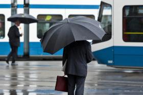 Banchieri con ombrello in attesa del tram
