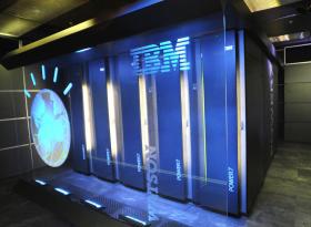 Grossi armadi metallici (che contengono schede madri e processori) decorati col marchio IBM, la scritta Watson, un illustrazione