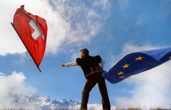un uomo lancia una bandiera svizzera e ne sventola una con i colori dell europa