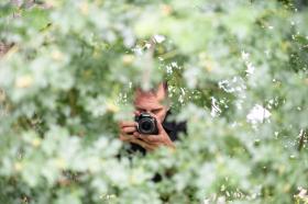 Uomo con fotocamera tra gli alberi