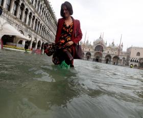 Donna cammina in piazza a Venezia; il livello dell acqua è oltre le sue gincchia