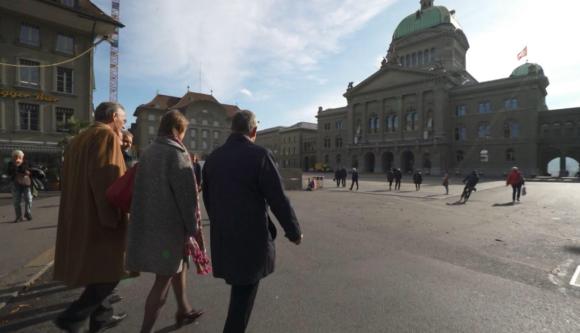 Persone camminano verso il palazzo federale a Berna