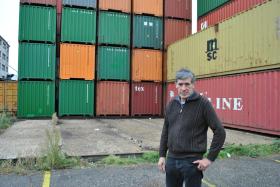un uomo davanti a un muro di container.