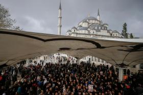 Folla di centinaia di persone, qualcuna con in mano un poster, riunita sotto un tendone nei pressi di una moschea