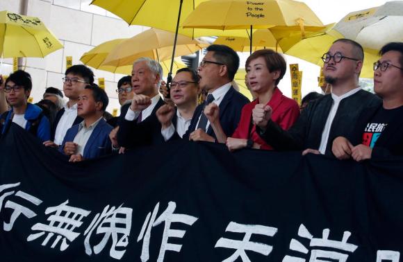 Alcuni leader con ombrelli gialli e striscioni stanno marciando verso il tribunale