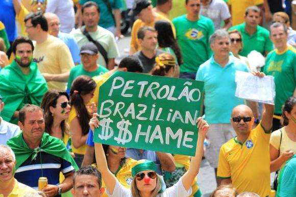 Gruppo di persone (vestiti perlopiù con colori verde-oro, che richiamano la bandiera del Brasile) in manifestazione di protesta