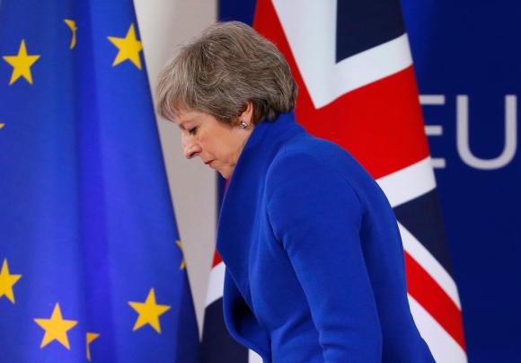 La premier britannca May di spalle con sullo sfondo le bandiere dell Ue e del Regno Unito