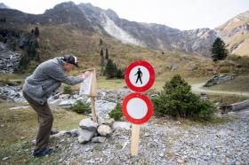 un uomo su un sentiero di montagna su cui è sistemato un cartello che vieta l accesso