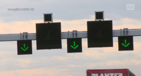 Primo piano di segnali luminosi installati ad arco sulle corsie autostradali; tutti e tre con freccia verde di via libera