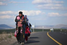 migranti in cammino sulla strada