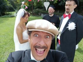 Il frontaliere Bussenghi scatta un selfie; dietro di lui il doganiere Bernasconi e la turista Amélie vestiti da sposi