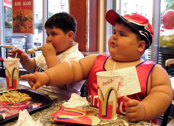 Due bambini decisamente obesi mentre mangiano in un fast food