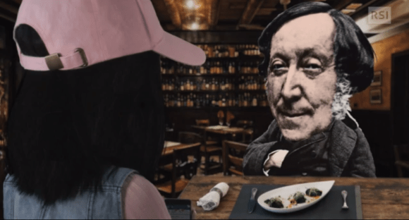 Figura di Rossini montata (stile collage) al tavolo di un osteria, di fronte a una ragazza di schiena con cappellino rosa