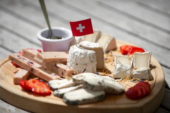 Diversi tipi di quello che, apparentemente, è formaggio, presentati su un tagliere con una mostarda e una bandierina svizzera