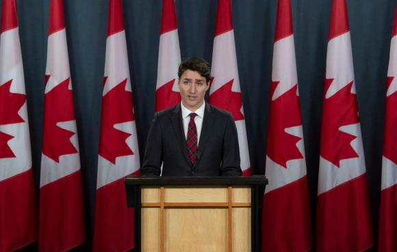 Il leader canadase Trudeau con dietro una serie di bandiere del suo paese