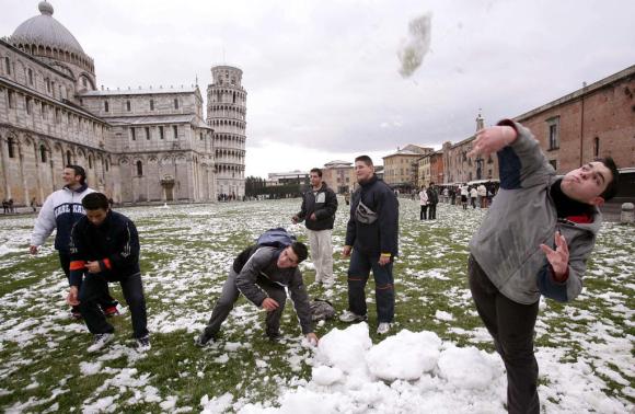 ragazzi giocano con la neve con sullo sfondo la torre di Pisa