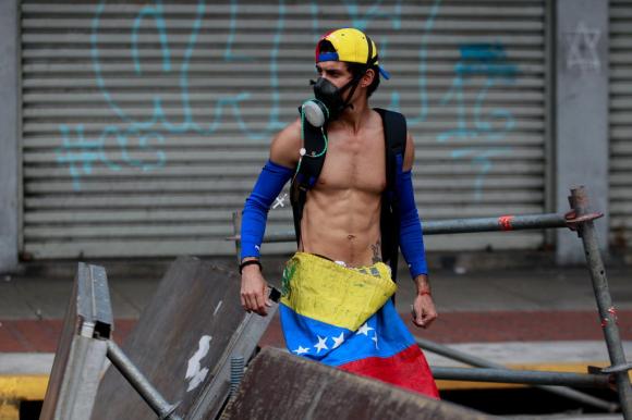 manifestante ricoperto di una bandiera venezuelana