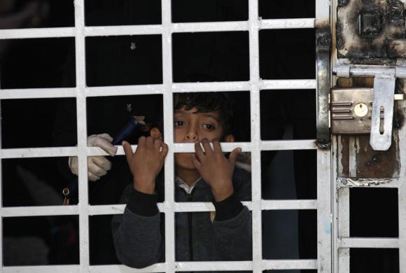 Un bambino dietro a una barriera, come se fosse in prigione