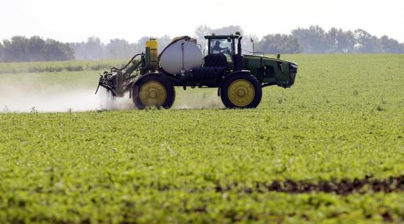 Un trattore sta spruzzando pesticidi in u campo di soia nello Iowa.