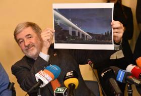 sindaco di genova mostra una foto con un ponte