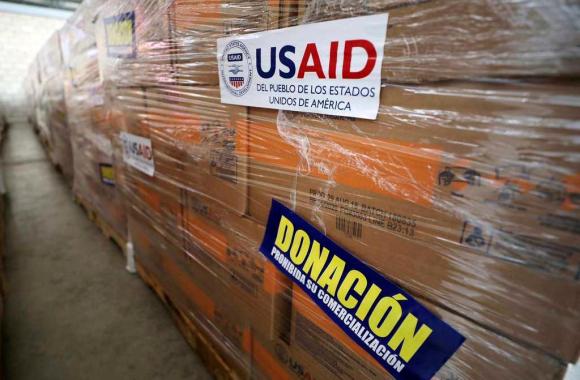 Primo piano di scatoloni rivestiti da cellophane con autoadesivi che riportano le scritte USAID e Donación