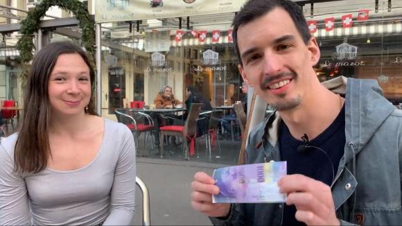 Ein Mann und eine Frau sitzen in einem Strassenkaffee, in den Händen eine 1000er-Note.