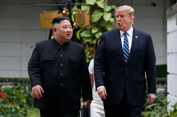 Trump e Kim mentre fanno una passeggiata dopo un primo incontro. Vestiti di scuro entrambi