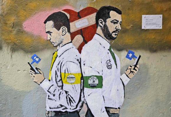 Di Maio e Salvini disegnati su un muto mentre giocano con il telefonino e cerca i vari like dei loro post